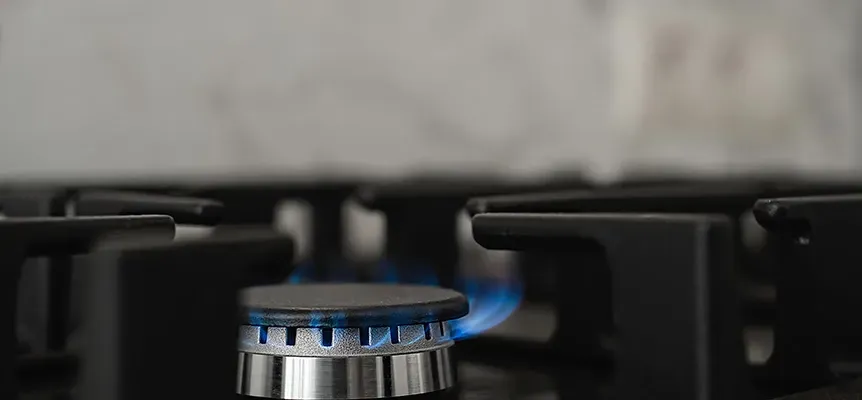 Kitchen stove burner lit with blue gas flame