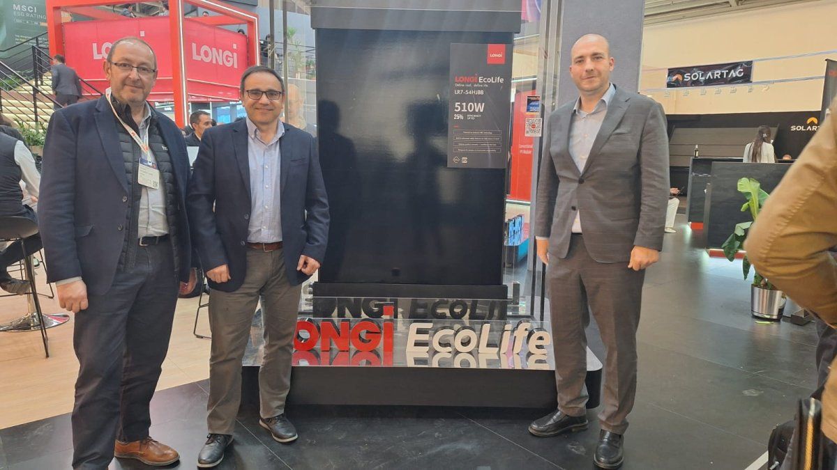 Tres professionals posen al costat d’un panell solar LONGi EcoLife de 510 W en un esdeveniment o fira del sector energètic.