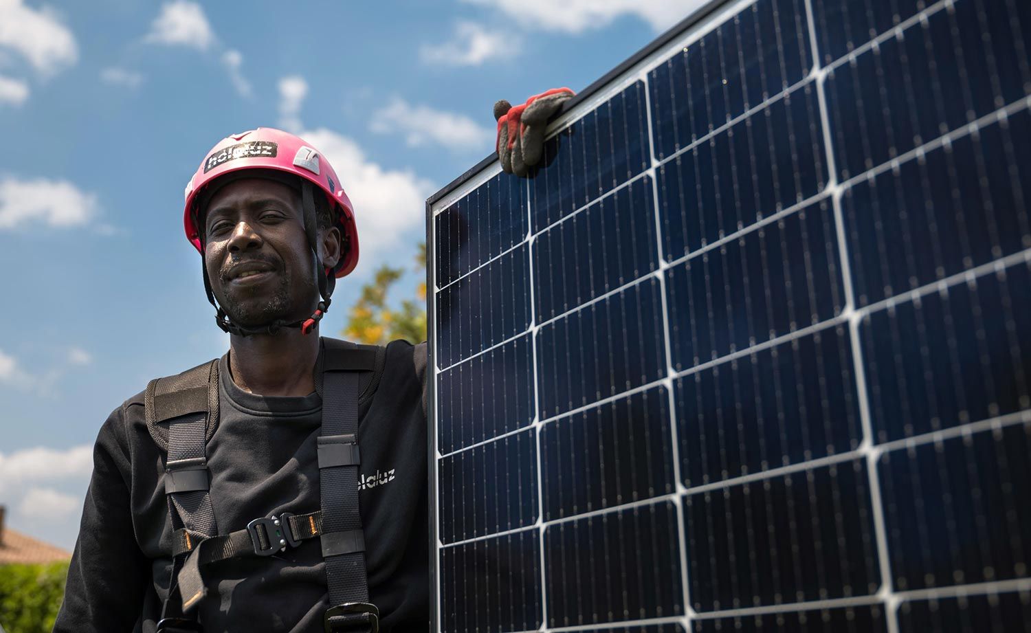 Técnico con equipo de seguridad sosteniendo un panel solar