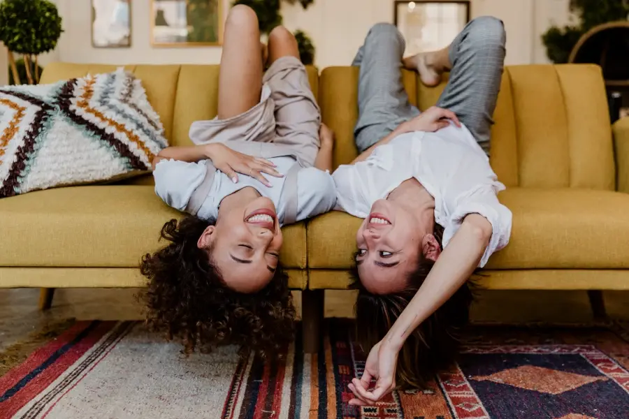 Mujeres sonrientes tumbadas boca abajo en un sofá