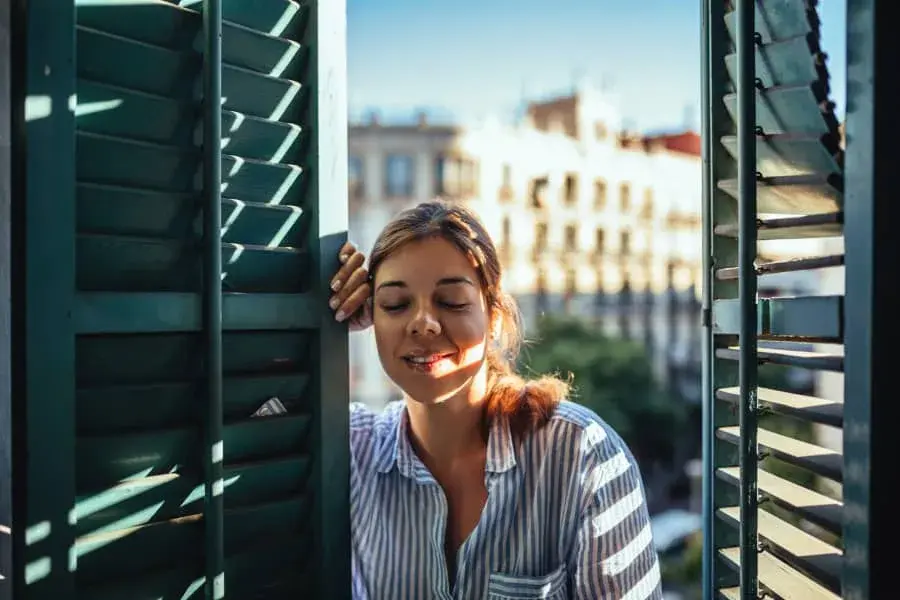 A person smiling as she gazes out of a window