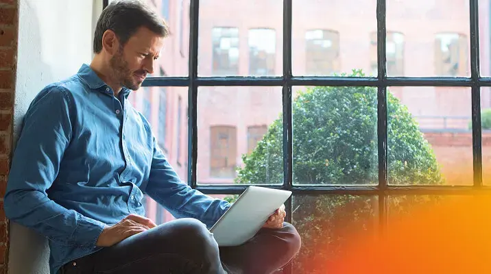 Man sitting with a tablet near a window