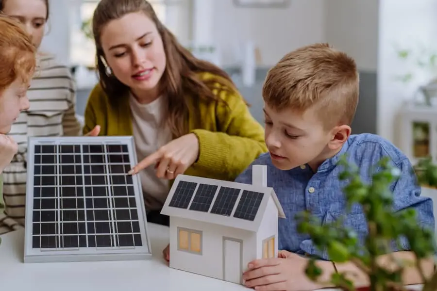 Una familia observando las maquetas de una placa solar y una casa