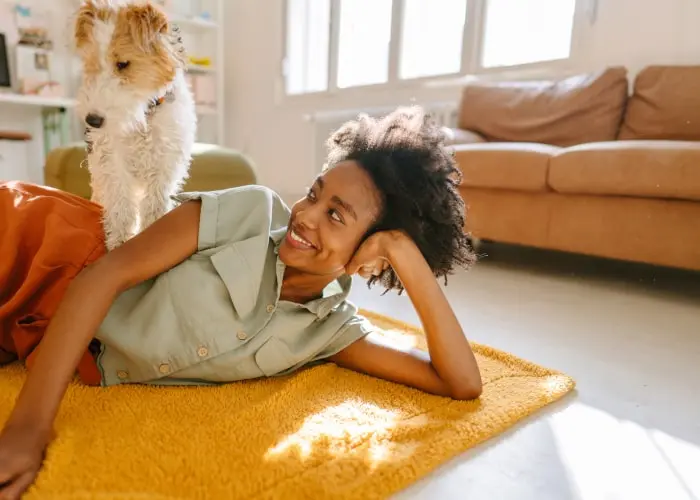 A woman peacefully resting on a rug with her dog