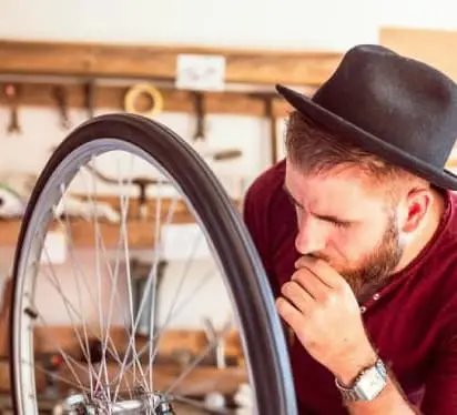 Imatge d'un noi arreglant una roda de bicicleta